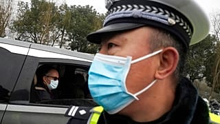 Peter Ben Embarek of the World Health Organization team passes by a Chinese police officer as he leaves in a convoy from the Baishazhou wholesale market