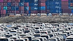 New cars are stored in front of containers at the 'logport' (logistic port) in Duisburg, Germany. Flle photo, Wednesday June 3, 2020.