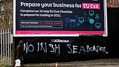 A man walks past graffiti reading "No Irish sea border" in the mainly loyalist Donegal road area of South Belfast, Northern Ireland, Saturday, Jan. 30, 2021.