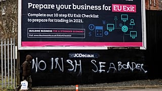 A man walks past graffiti reading "No Irish sea border" in the mainly loyalist Donegal road area of South Belfast, Northern Ireland, Saturday, Jan. 30, 2021.
