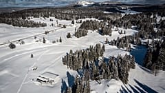 En bas, à gauche, une remontée de la station de Dôle en Suisse. Devant celle-ci, le parking de celle-ci en France, sous la neige le 26 janvier 2021