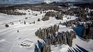 En bas, à gauche, une remontée de la station de Dôle en Suisse. Devant celle-ci, le parking de celle-ci en France, sous la neige le 26 janvier 2021