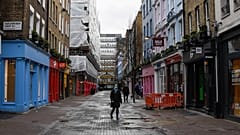 A woman wears a face mask as she walks in a deserted Carnaby Street, in London, Wednesday, Feb. 3, 2021.