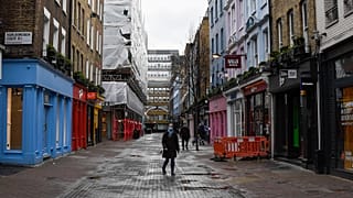 A woman wears a face mask as she walks in a deserted Carnaby Street, in London, Wednesday, Feb. 3, 2021.