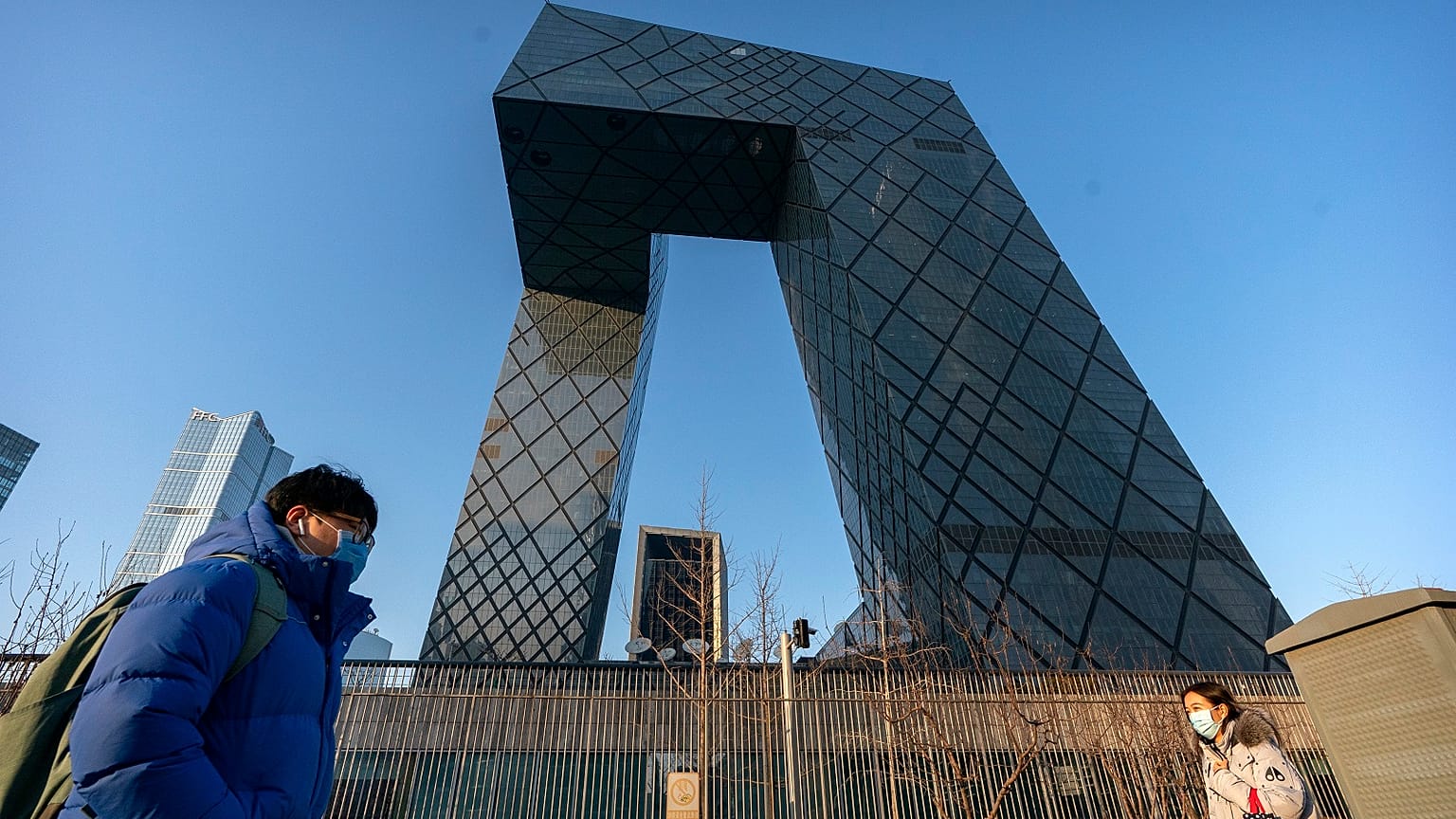 People walk past the CCTV Headquarters building, the home of Chinese state-run television network CCTV and its overseas arm CGTN, in Beijing on Feb. 4, 2021.