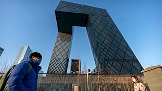 People walk past the CCTV Headquarters building, the home of Chinese state-run television network CCTV and its overseas arm CGTN, in Beijing on Feb. 4, 2021.