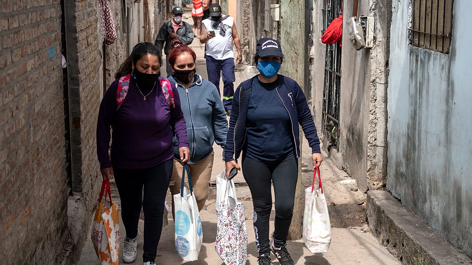 Unas mujeres llevan bolsas con raciones de comida de un comedor social para alimentar a las personas más afectadas por la crisis económica.