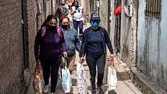 Unas mujeres llevan bolsas con raciones de comida de un comedor social para alimentar a las personas más afectadas por la crisis económica.