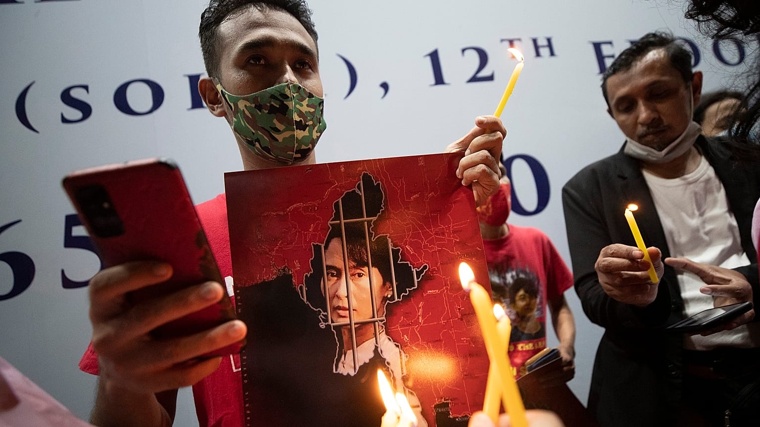 Myanmar nationals in Thailand hold pictures of Aung San Suu Kyi and lit candles during a protest in front of the Myanmar Embassy in Bangkok, Feb. 4, 2021.