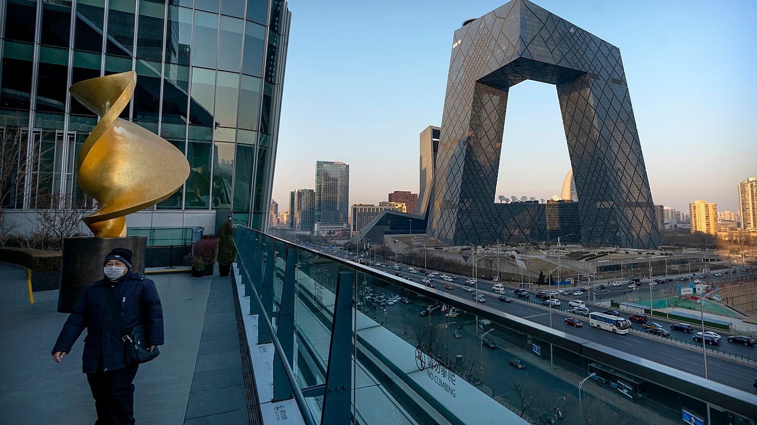 A man walks along an observation deck near the CCTV Headquarters building, the home of Chinese state-run television network CCTV and its overseas arm CGTN, in Beijing.