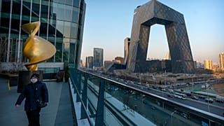 A man walks along an observation deck near the CCTV Headquarters building, the home of Chinese state-run television network CCTV and its overseas arm CGTN, in Beijing.