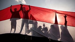 انعكاس ظل أشخاص يقفون وراء العلم اليمني خلال احتفالات سبتمبر شمال اليمن. 2016/09/26