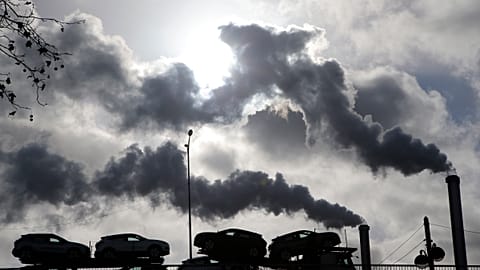  In this Friday, Nov. 30, 2018 file photo smoke rises from a factory as a truck loaded with cars crosses a bridge in Paris, France.