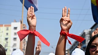 Manifestantes usam fitas vermelhas, cor do partido de Aung San Suu Kyi e fazem a saudação da resistência