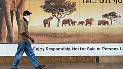 A man wearing a face covering, walks past a logo on the street in Alberton, near Johannesburg, South Africa, Thursday, Jan. 7, 2021.