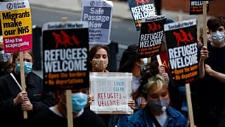 Protestors hold placards during a pro-migrants protest outside the government's Home Office in London, Tuesday, Aug. 25, 2020