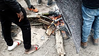 Des exilés se réchauffant au coin du feu dans un camp de fortune, à Calais, dans le nord de la France, le 31 janvier 2020.