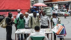 موطنون تنزانيون يقفون أمام بائع جرائد من دون التقيد بإجراءات التباعد الاجتماعي للحد من انتشار فيروس كورونا 