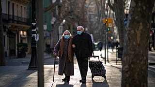 Una pareja con mascarillas camina por un bulevar en Barcelona, España, el 27 de enero de 2021.