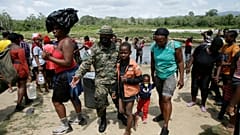 Migrantes son recibidos por un oficial de la policía fronteriza panameño en la localidad de Bajo Chiquito en Darién, Panamá, el 10 de febrero de 2021.