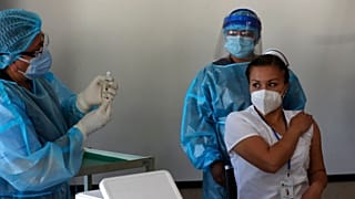 Nurse Cristina Chango receives her first dose of the Pfizer-BioNtech vaccine against COVID-19 at the Pablo Arturo Suarez Hospital in Quito, Ecuador, Thursday, Jan. 21, 2021.