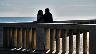 عاشقان إيطاليان لم ينسهما الحب أنّهما في زمن كورونا إذ يرتدي كلٌ منهما كمامة تحميه من الفيروس
