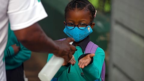 Une élève se désinfecte les mains avant de rentrer en classe pour la rentrée, le 15 février 2021, Johannesburg, Afrique du Sud