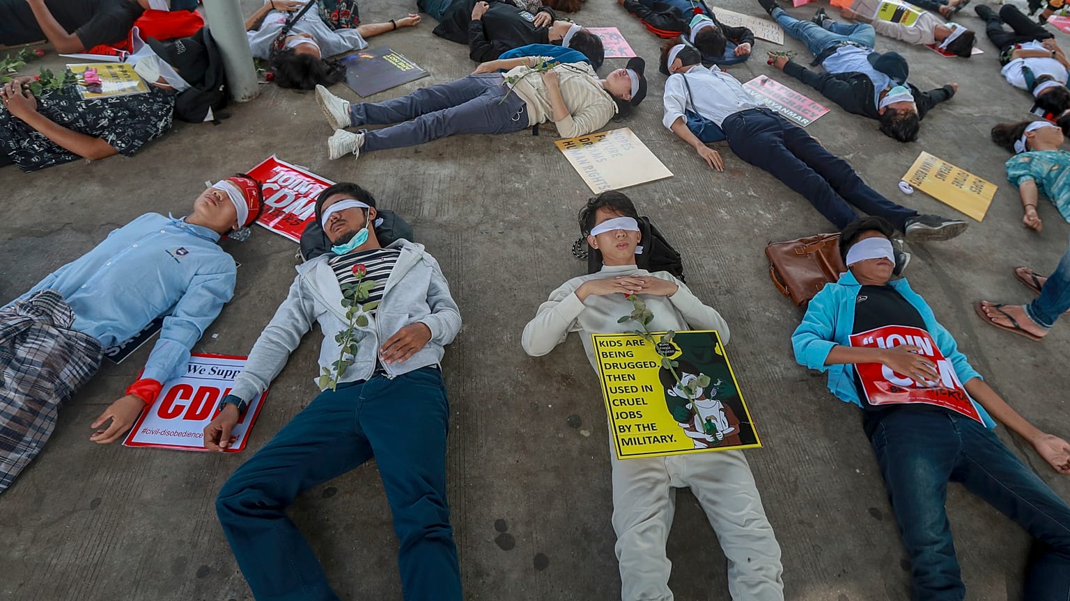 Demonstrators, with eyes blindfolded, lie down in the street to a protest a military coup in Yangon, Myanmar, Tuesday, Feb. 16, 2021. 