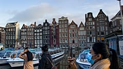 Maszkos nő fényképezi a leállított turistahajókat Amszterdamban 2021. február 4-én