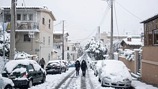People walk in a street of Petralona neighborhood of Athens