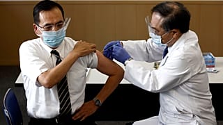Tokyo Medical Center director Kazuhiro Araki, left, receives a dose of COVID-19 vaccine in Tokyo Wednesday, Feb. 17, 2021.