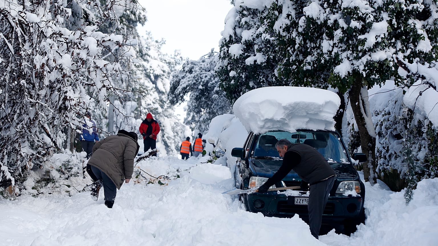 Los residentes tratan de limpiar una calle  después de una fuerte nevada en el suburbio de Dionysos, al norte de Atenas, el  17 de febrero de 2021. 
