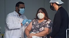 El ministro de Salud de El Salvador, Francisco Alabi, procede a vacunar a una enfermera ante la mirada atenta del presidente, Nayib Bukele.