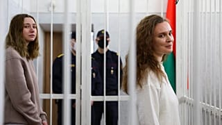 Journalists Katsiaryna Andreyeva, right, and Daria Chultsova stand inside a defendants' cage in a court room in Minsk, Belarus, Thursday, Feb. 18, 2021.