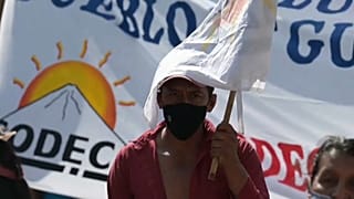 Un manifestante se protege del sol con una pancarta de tela durante la protesta contra el presidente de Guatemala, Alejandro Giammattei, en Ciudad de Guatemala.