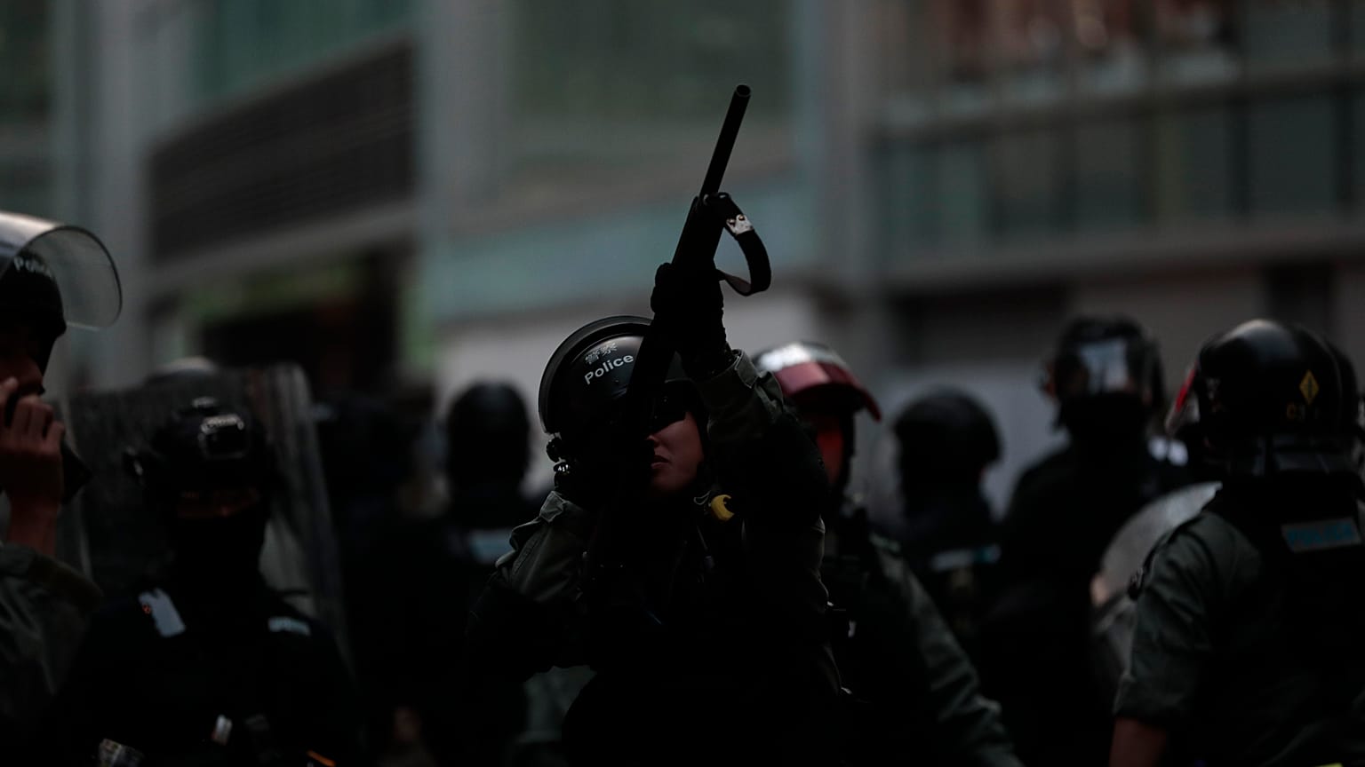 A Hong Kong police officer aiming his weapon at demonstrators on a pedestrian bridge in 2019.