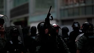 A Hong Kong police officer aiming his weapon at demonstrators on a pedestrian bridge in 2019.