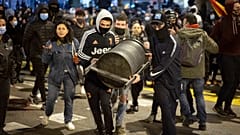 Demonstrators carry a rubbish bin to throw it agains police officers protecting a national police station during clashes following a protest condemning the arrest of a rapper.
