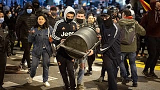 Demonstrators carry a rubbish bin to throw it agains police officers protecting a national police station during clashes following a protest condemning the arrest of a rapper.
