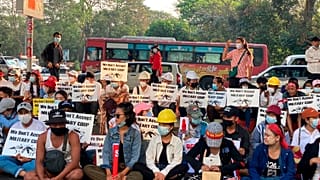 Anti-coup protesters hold signs that read "We Don't Accept Military Coup" as they gather under an elevated roadway outside the Hledan Centre in Yangon, Myanmar Monday, Feb. 22