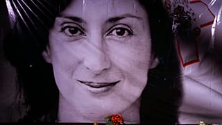 flowers and a candle lie in front of a portrait of slain investigative journalist Daphne Caruana Galizia during a vigil outside the law courts in Valletta, Malta