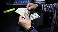 یک صراف ایرانی در حال شمارش دلار آمریکا