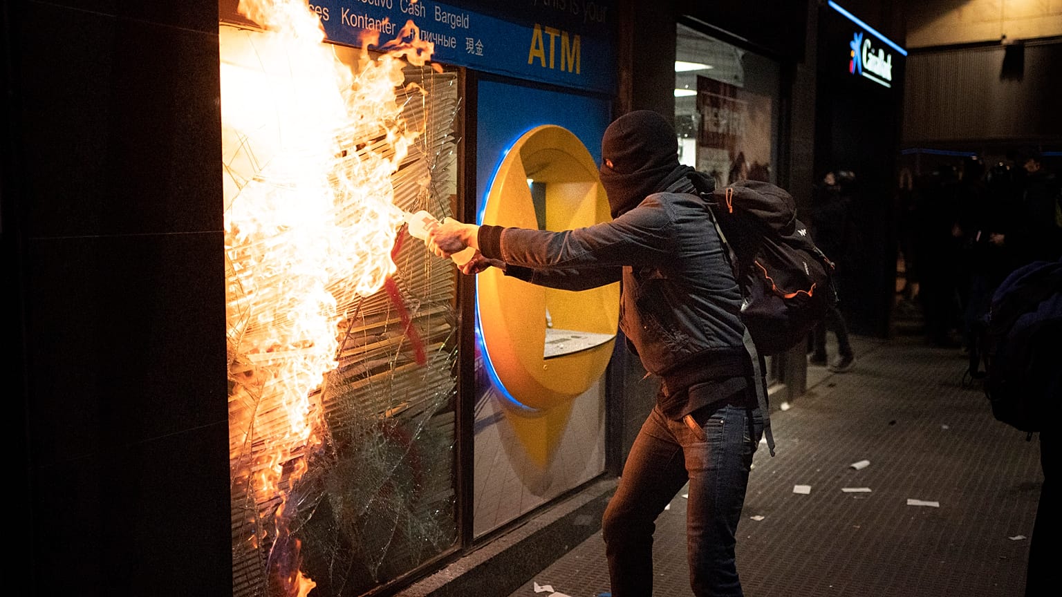 Манифестант поджигает банк в ходе протестов против заключения в тюрьму Пабло Аселя, 27 февраля 2021 г.