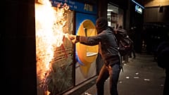 Манифестант поджигает банк в ходе протестов против заключения в тюрьму Пабло Аселя, 27 февраля 2021 г.