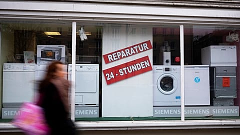 A person walks past a shop offering the repair of electronic equipment and domestic appliances in Berlin, Germany, Friday, Feb. 26, 2021.