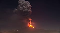 Flames and smoke billowing from a crater, as seen from the southern side of the Mt Etna volcano, tower over the city of Pedara, Sicily, Wednesday night, Feb. 24, 2021.