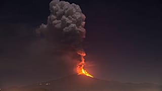 Flames and smoke billowing from a crater, as seen from the southern side of the Mt Etna volcano, tower over the city of Pedara, Sicily, Wednesday night, Feb. 24, 2021.