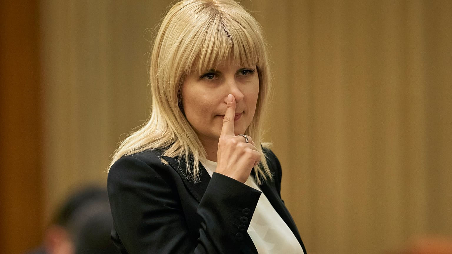 In this Monday, Feb. 9, 2015 file photo, Elena Udrea touches her nose after delivering a speech in parliament pleading with fellow lawmakers not to approve her arrest.