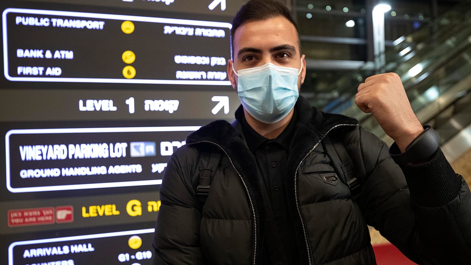 A traveler holds up an electronic monitoring bracelet
