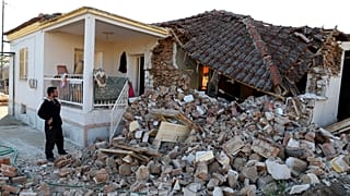 Ein Mann steht neben seinem zerstörten Haus im griechischen Mesochori.